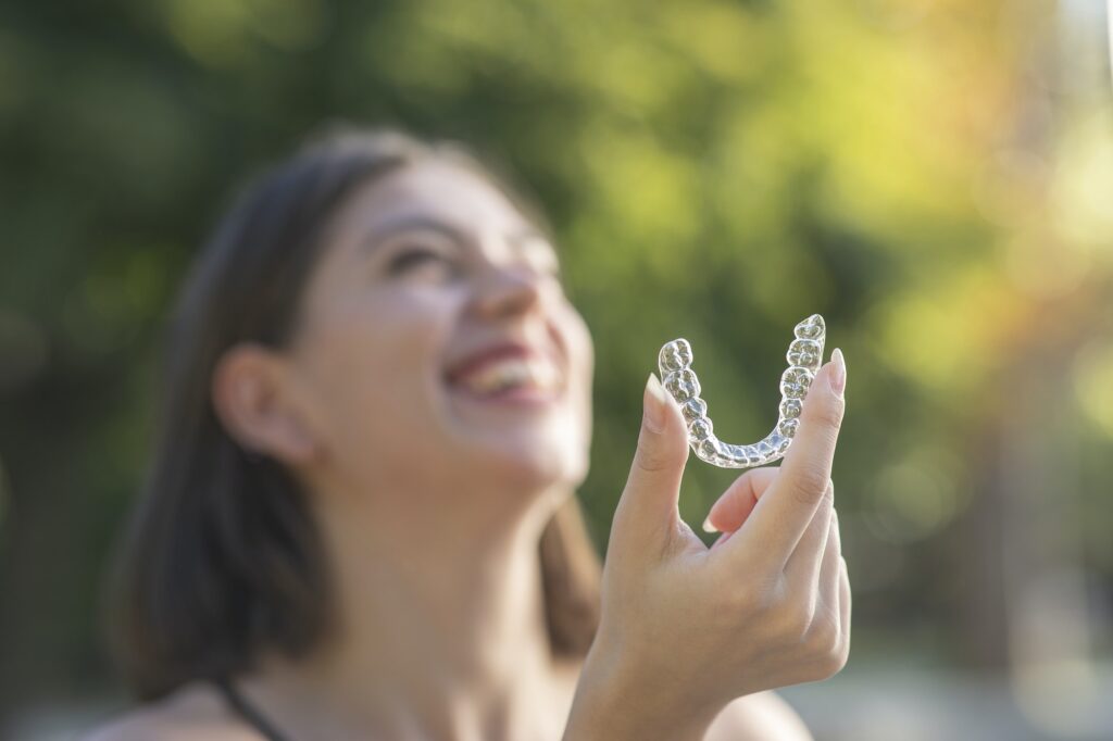 Beautiful smiling Turkish woman is holding an invisalign bracer